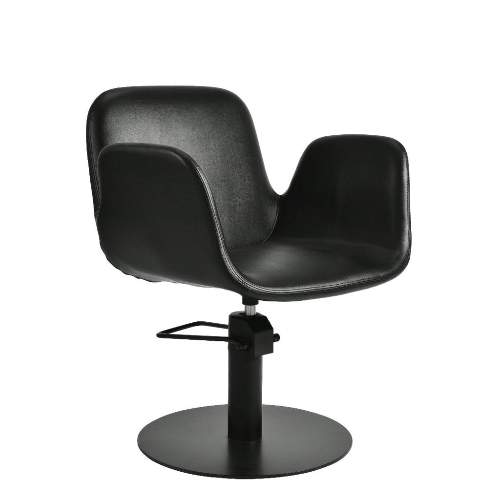 A modern black salon chair with a curved, sculptural seat and backrest, mounted on a black hydraulic swivel base with a circular footrest, shown against a plain white background.