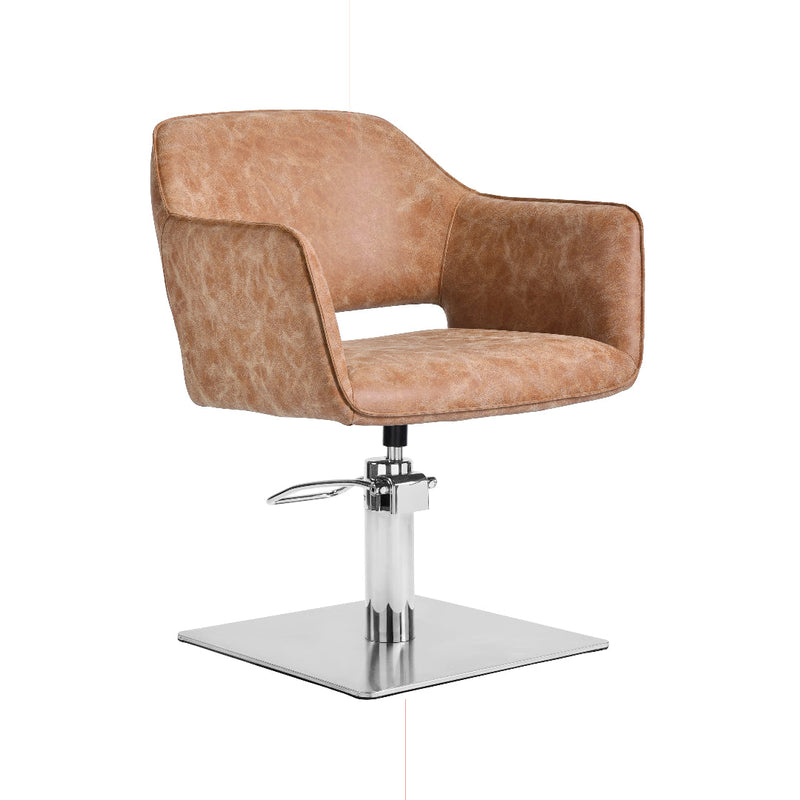 A modern salon
 chair with a curved, cushioned back and seat upholstered in a textured tan faux leather, supported by a chrome-plated hydraulic lift base with a square platform.