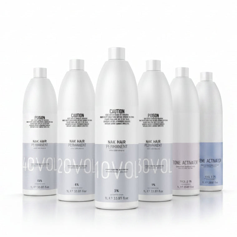 Six white bottles of Nix Hair permanent hair color developer and developer activator, arranged in a row against a white background. The bottles are labeled with different developer strengths (40Vol, 50Vol, 60Vol, 70Vol, 80Vol) and include a purple tone activator bottle on the right.